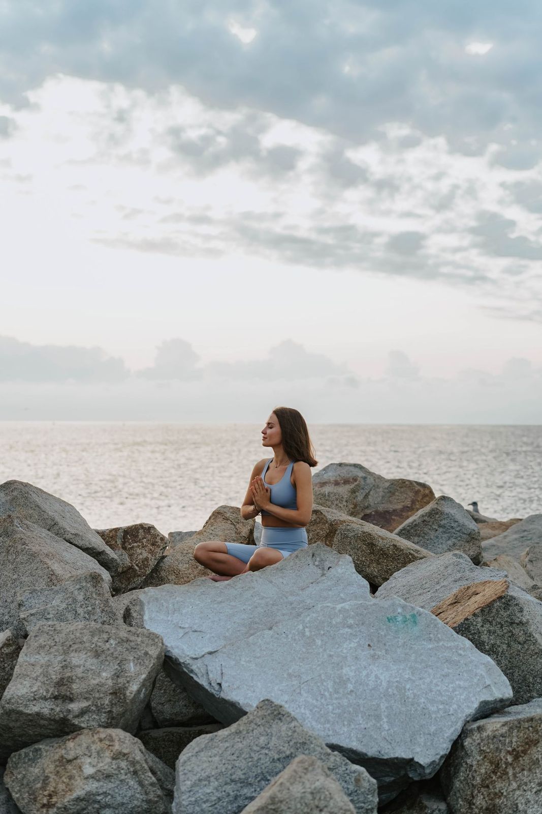A woman meditating on rocks beside the sea