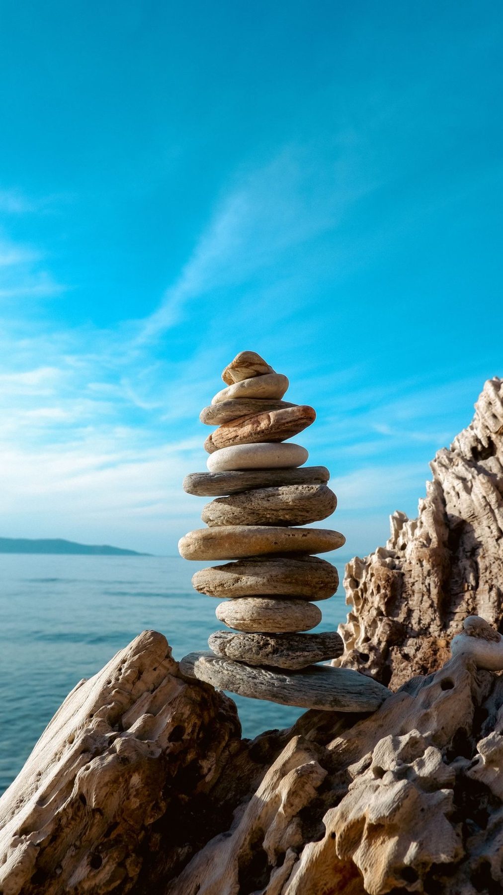 Balanced stone cairn against a bright blue sky