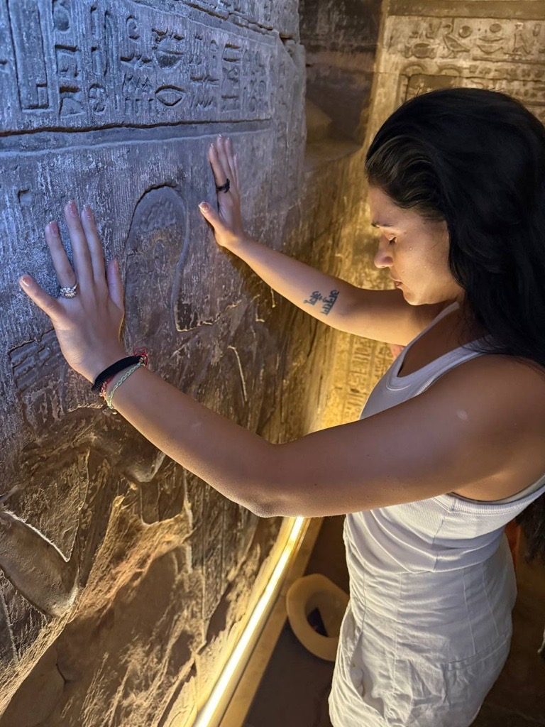 Esha resting her hands on carved stone in an ancient temple