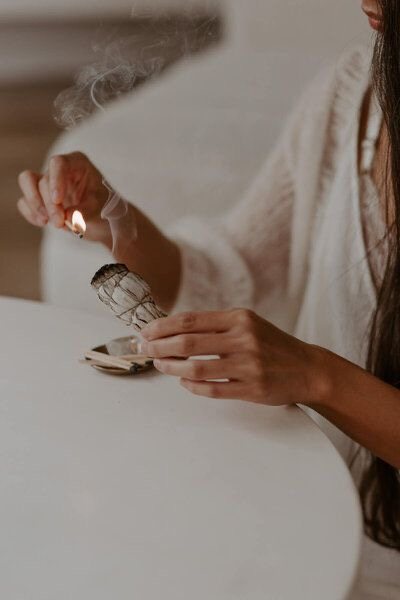 Hands lighting a sage bundle for a cleansing ritual