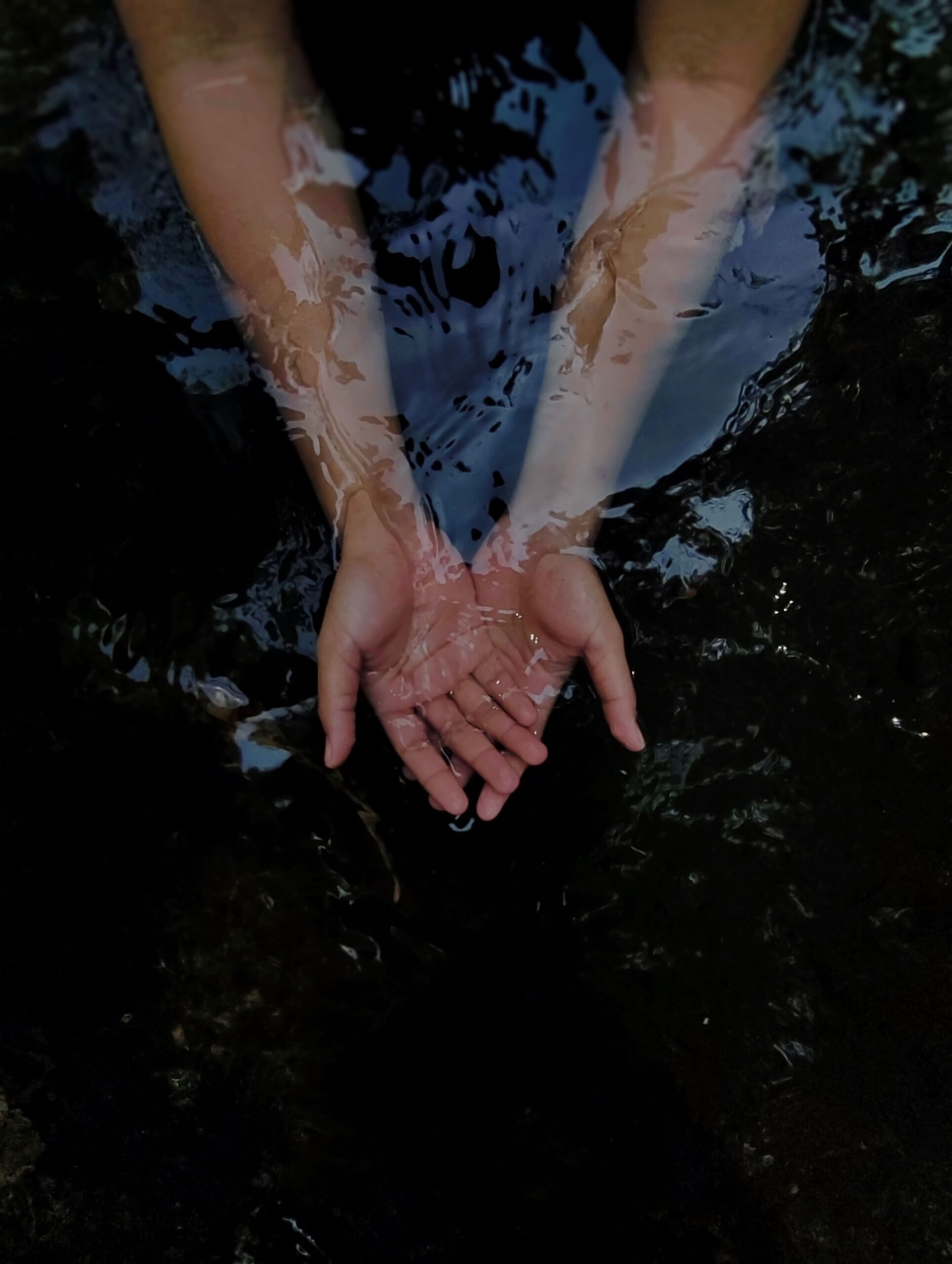Cupped hands holding water in soft light